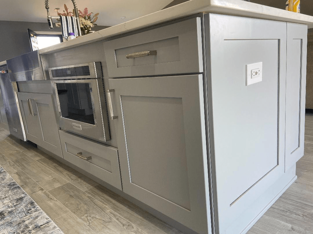 A kitchen island with stainless steel appliances and gray cabinets.