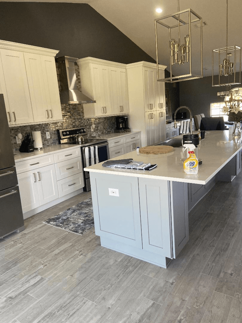 A kitchen with white cabinets , stainless steel appliances , and a large island.