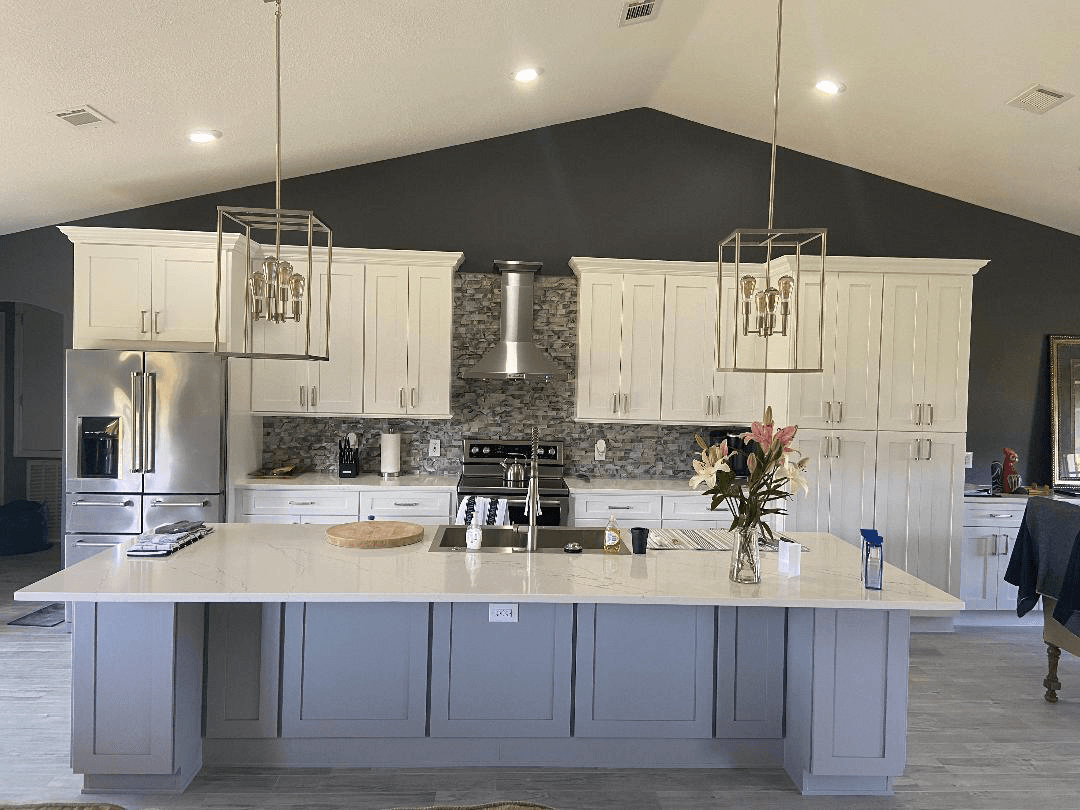 A kitchen with white cabinets , stainless steel appliances , and a large island.