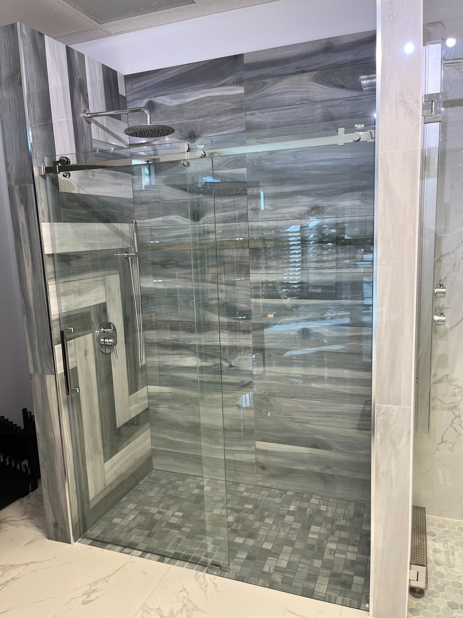 A bathroom with a walk in shower with a glass door.