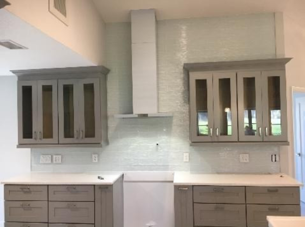 A kitchen with gray cabinets and white counter tops