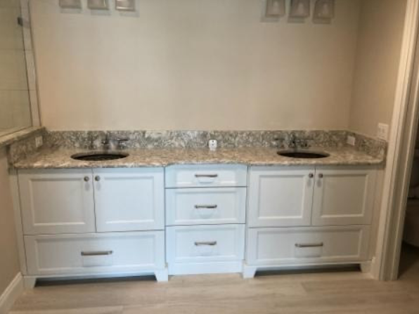 A bathroom with two sinks and white cabinets.