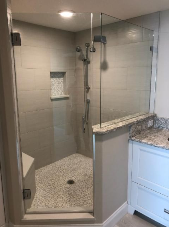 A bathroom with a walk in shower and a vanity.
