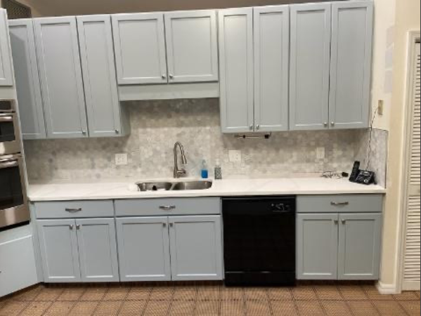 A kitchen with light blue cabinets , a sink , and a dishwasher.