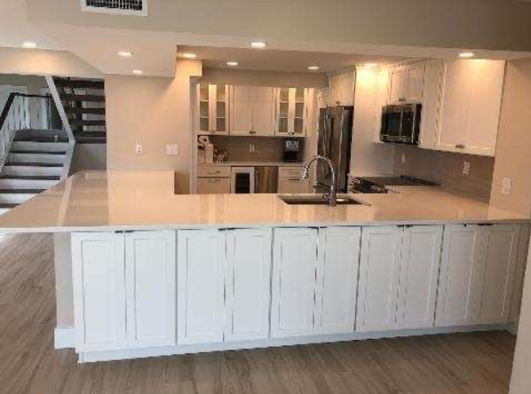 A kitchen with white cabinets , a sink , and a refrigerator.