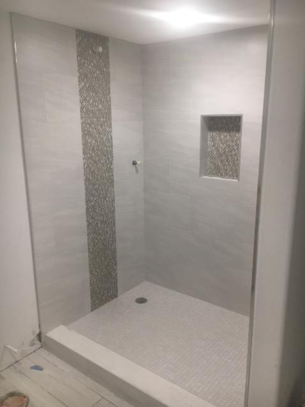 A bathroom with a walk in shower with a glass door.