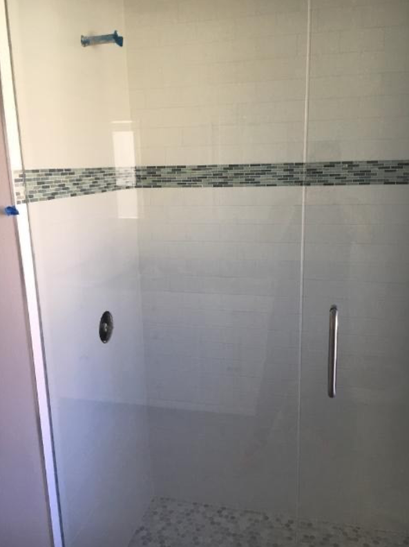 A shower stall with a glass door and a tile border.