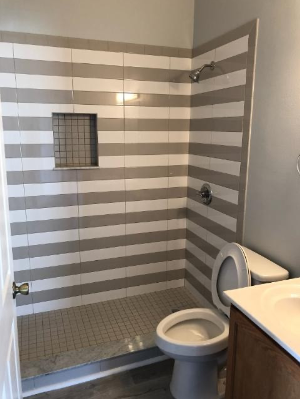A bathroom with striped tiles and a toilet