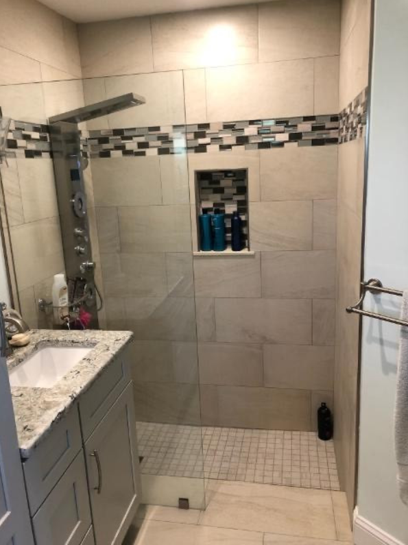 A bathroom with a walk in shower , sink and mirror.