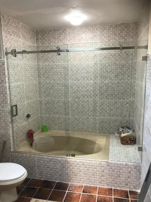 A bathroom with a tub , toilet , and shower stall.