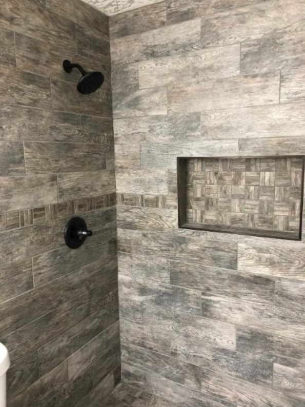 A shower with a black shower head and a niche in the wall.