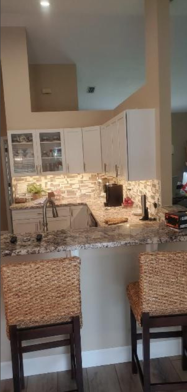 A kitchen with a bar and two wicker chairs.
