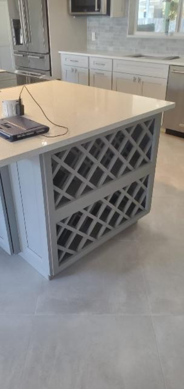 A kitchen with a large island with wine racks underneath it.