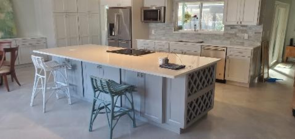 A kitchen with a large island and stools in it.