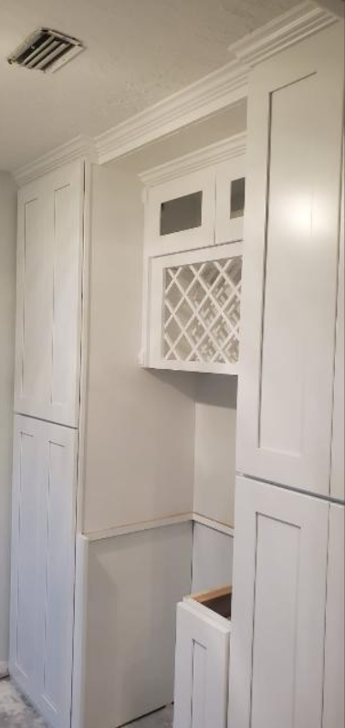 A kitchen with white cabinets and a wine rack on the wall.