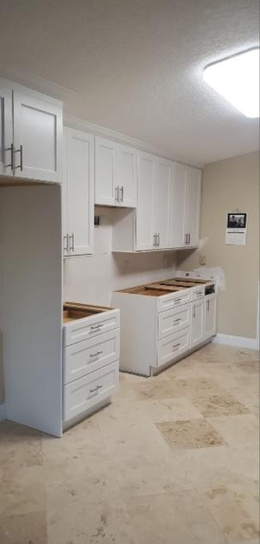 A kitchen with white cabinets and a tile floor.
