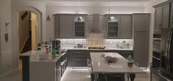 A kitchen with gray cabinets , stainless steel appliances , a table and chairs.