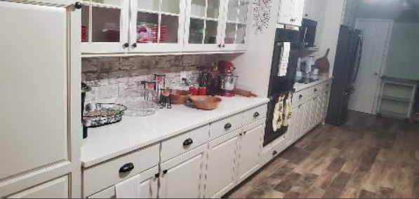 A kitchen with white cabinets and a black refrigerator.