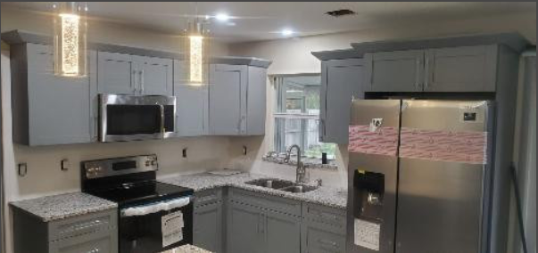 A kitchen with stainless steel appliances and gray cabinets.