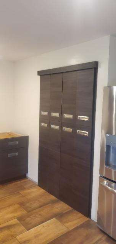 A kitchen with a refrigerator , dishwasher , and sliding doors.