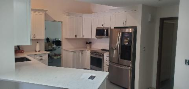 A kitchen with white cabinets and stainless steel appliances.