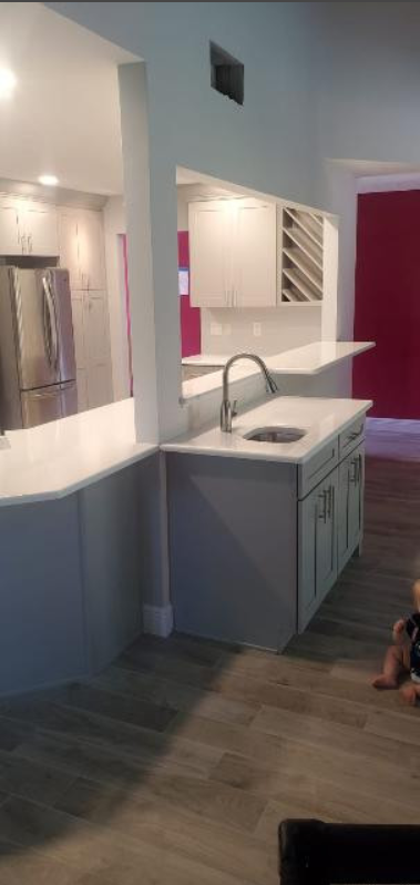 A kitchen with white cabinets , a sink , and a refrigerator.