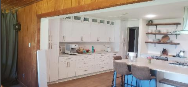 A kitchen with white cabinets and a wooden wall.