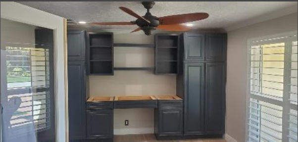 A room with a ceiling fan and a desk in it.