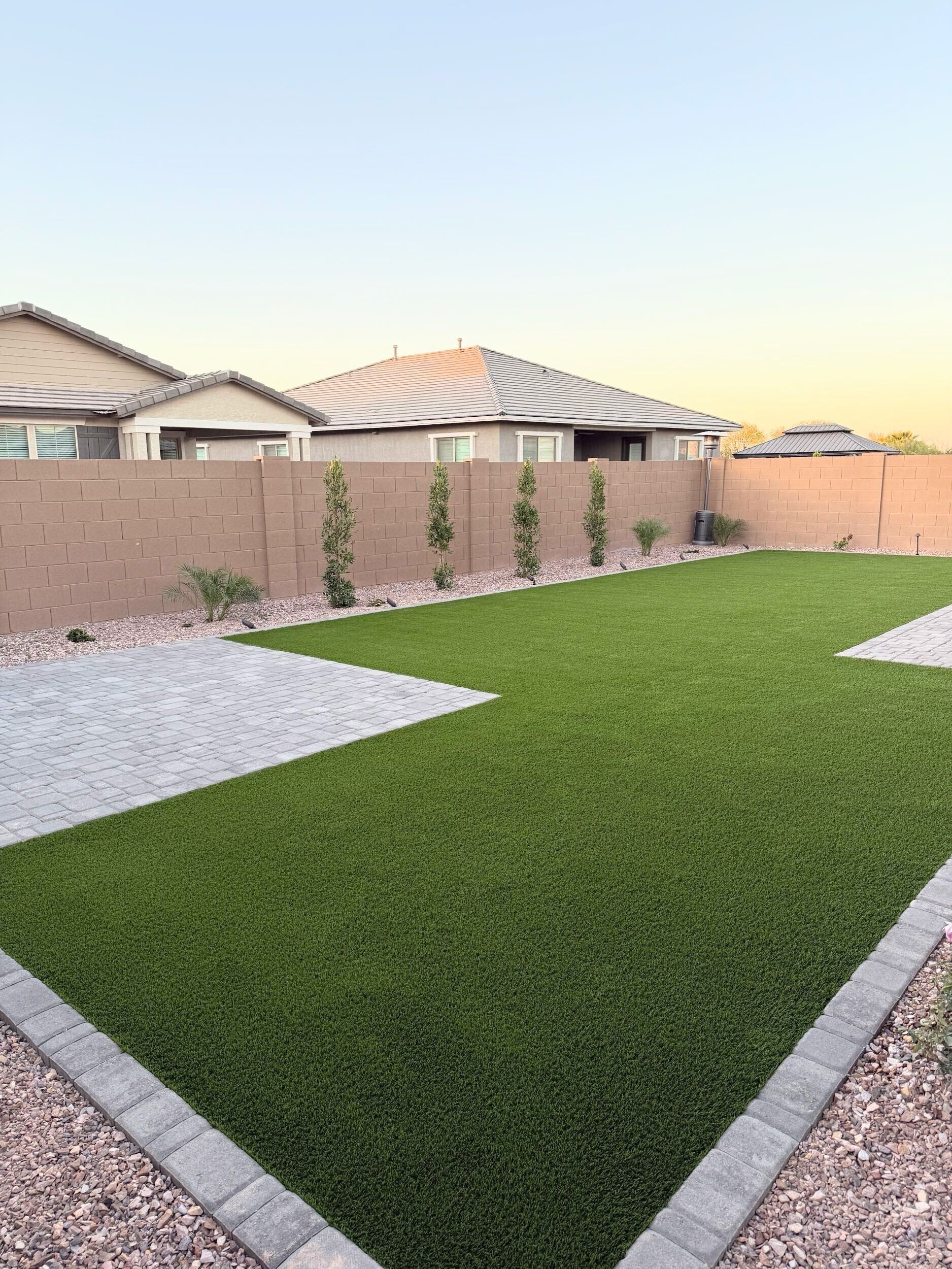 A backyard with a lot of grass and a house in the background.