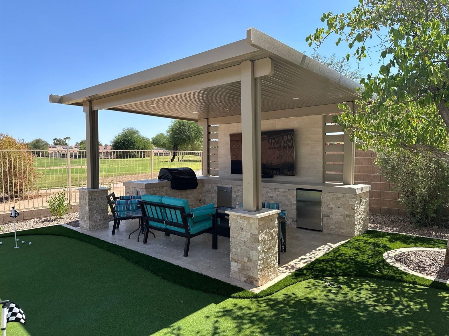 A backyard with a covered patio area and a putting green.