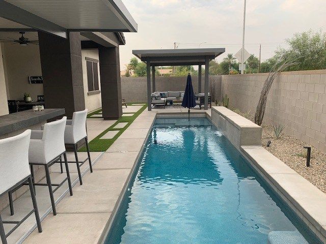 A very long swimming pool with a bar and chairs surrounding it