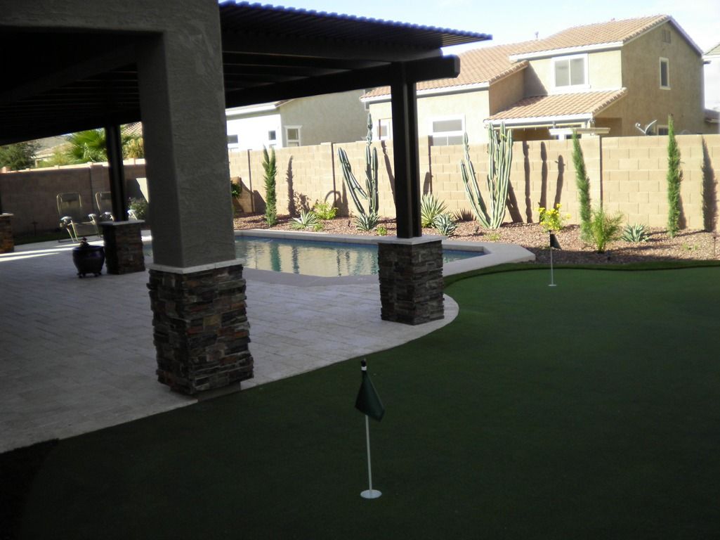 A backyard with a putting green and a pool