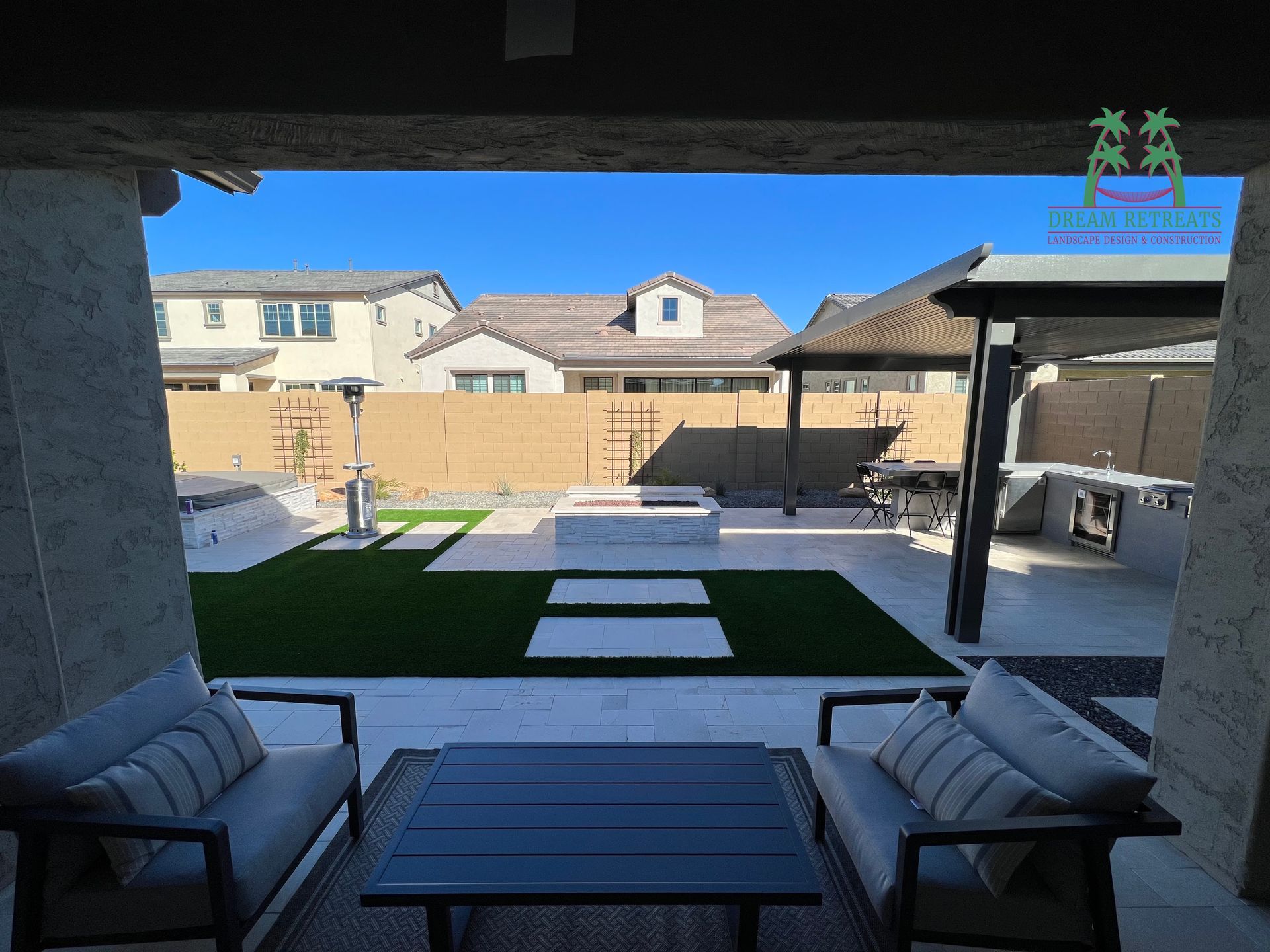 A view of a backyard from a patio with a couch , table and chairs.