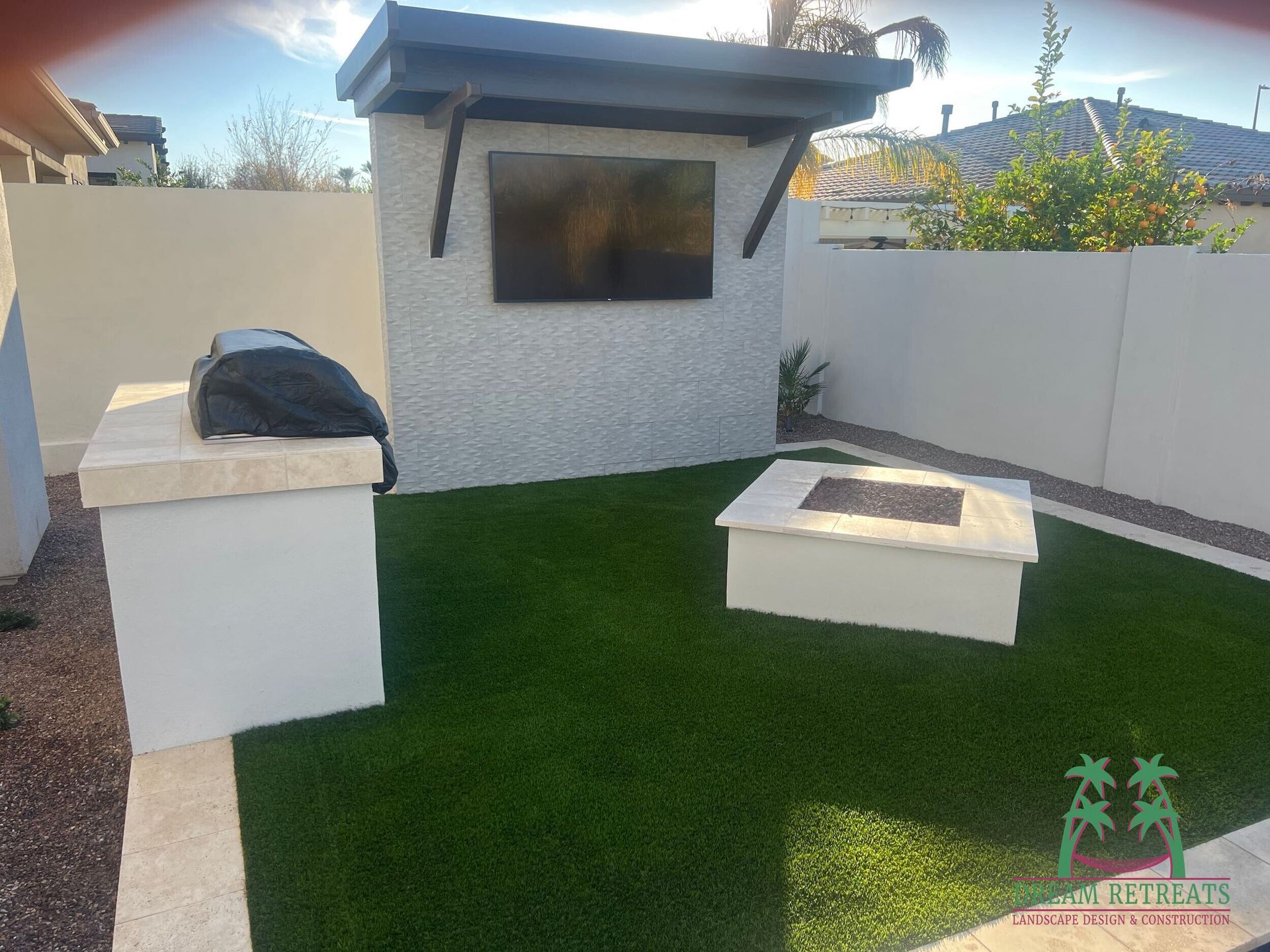 A backyard with a fire pit , grill and television.