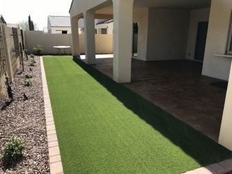 A house with a covered patio and a lush green lawn