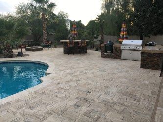 A patio with a swimming pool and a grill.