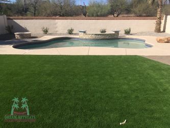A backyard with a swimming pool and a lush green lawn.