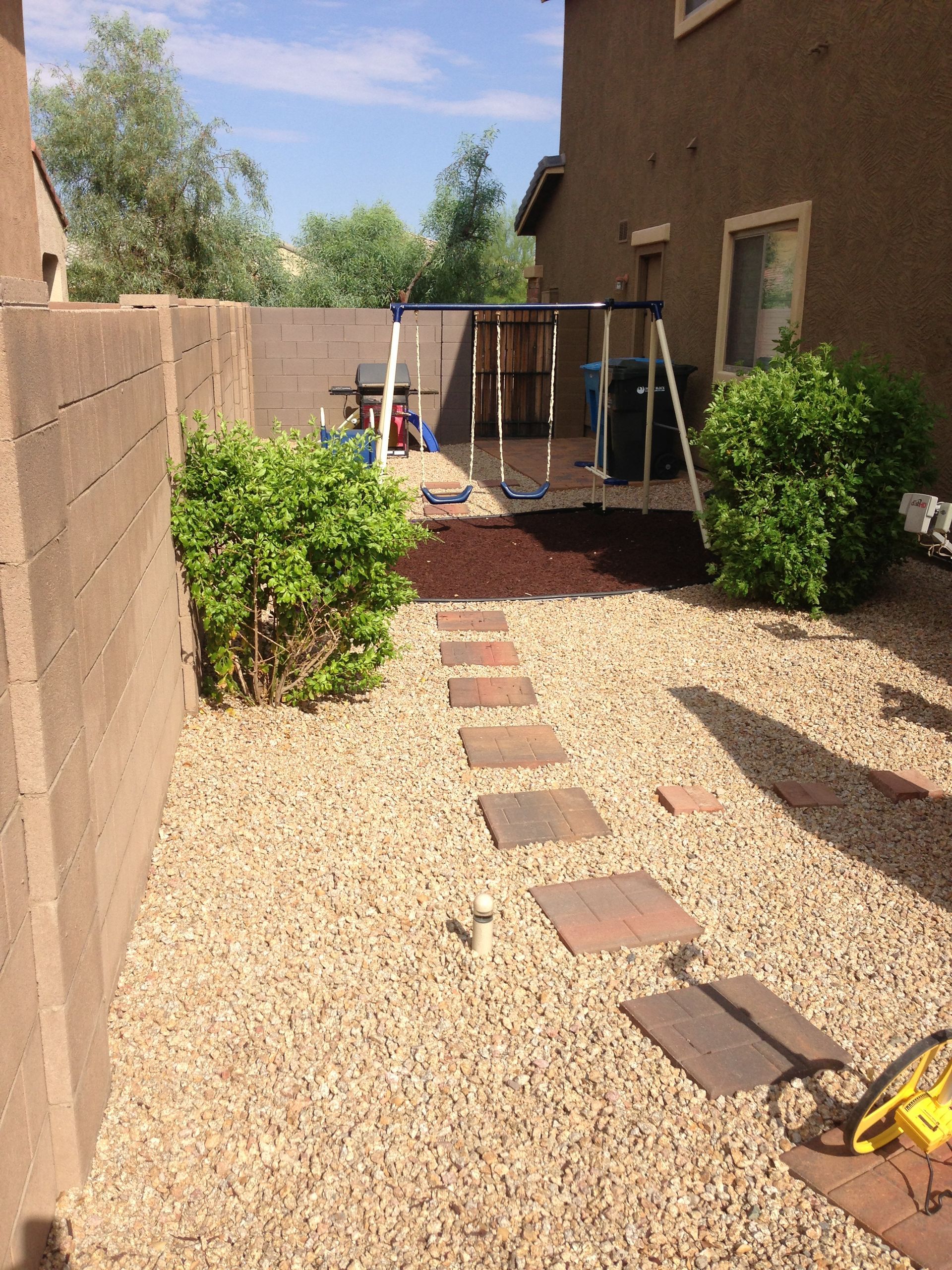A backyard with a swing set and a lawn mower