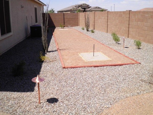 A yard with a brick fence and a bowling alley