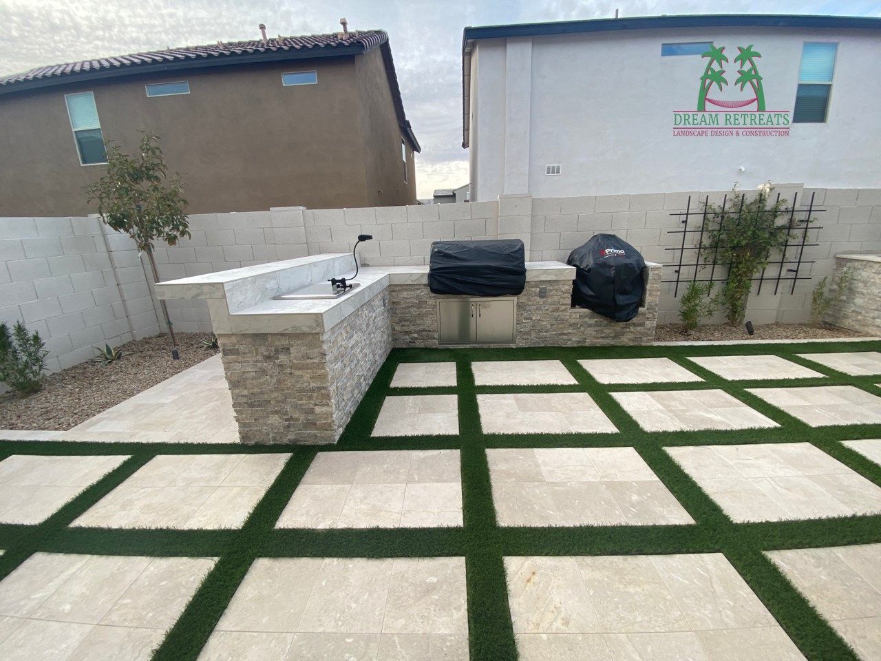 A patio with a grill and a sink in the backyard of a house.