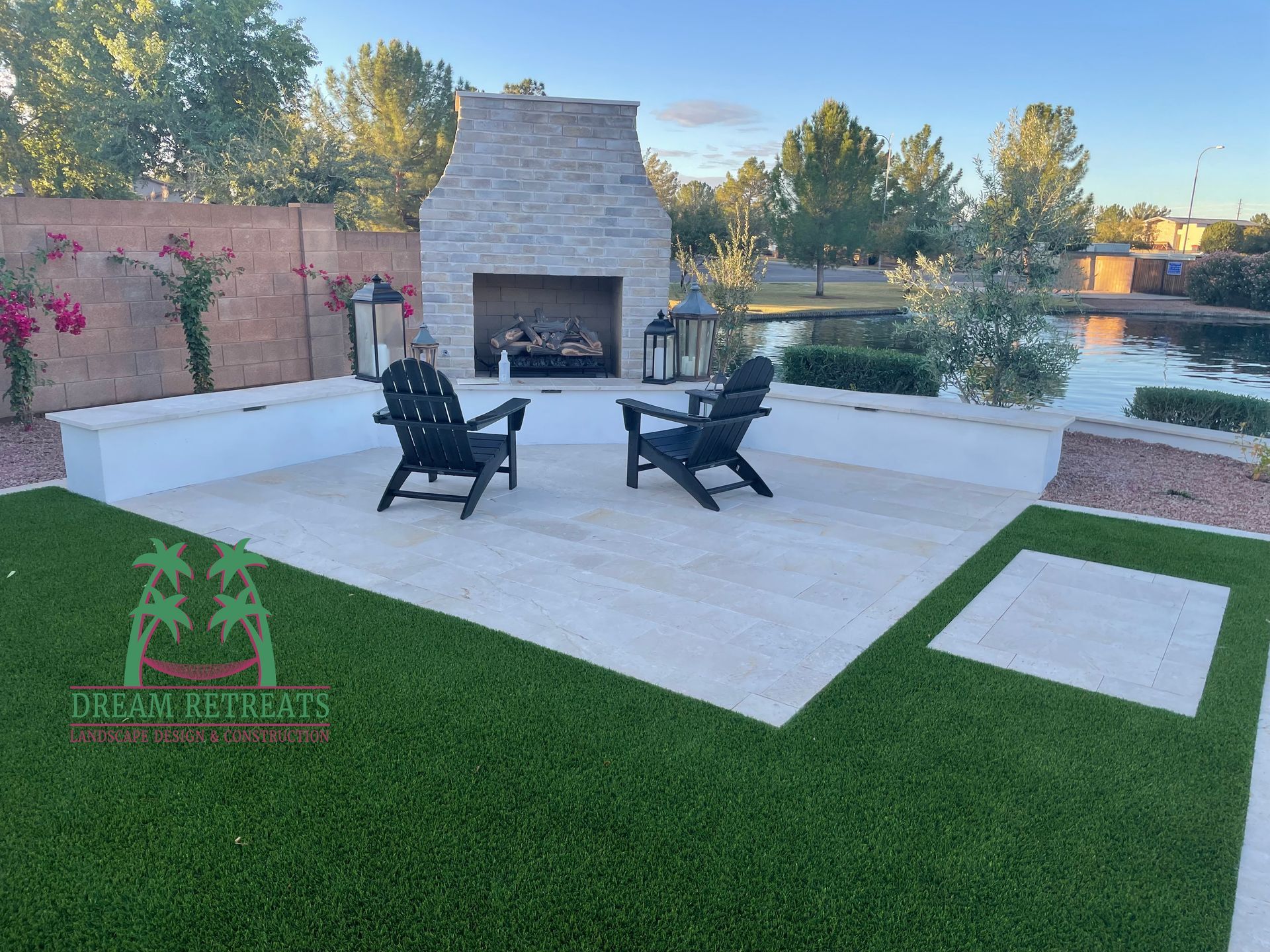 Two chairs are sitting in front of a fireplace in a backyard.