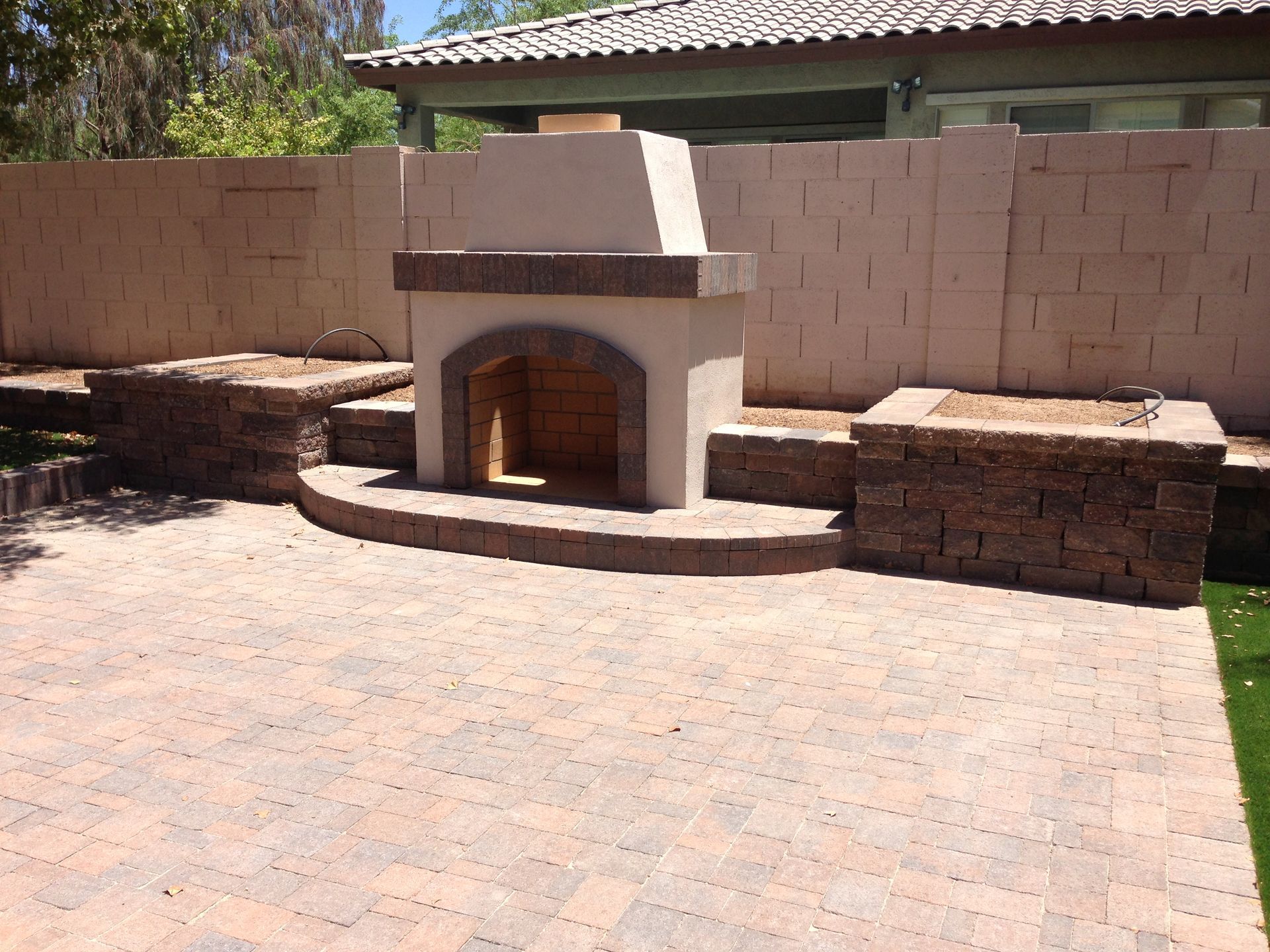 A brick patio with a fireplace in the middle