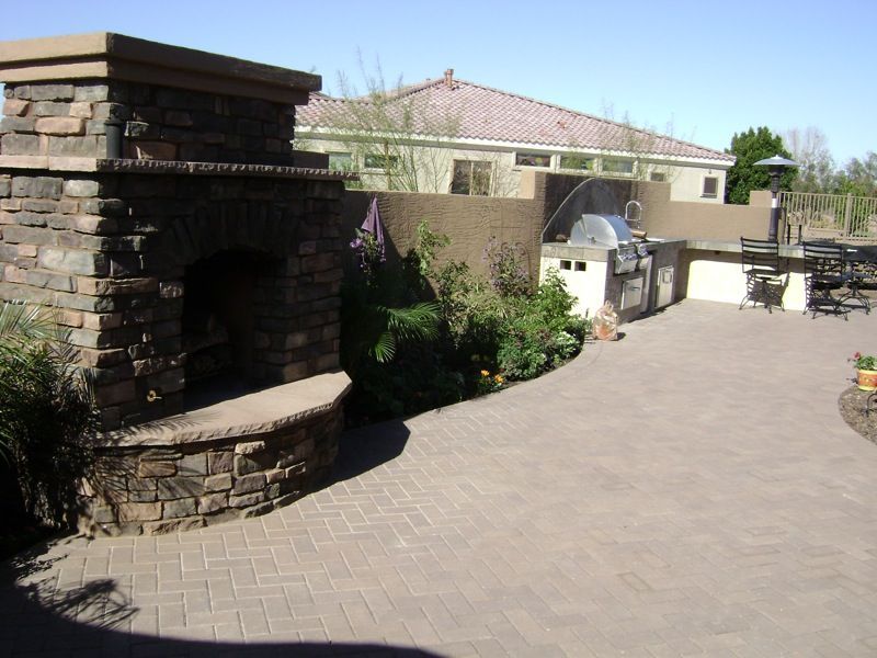 A brick patio with a fireplace and a grill