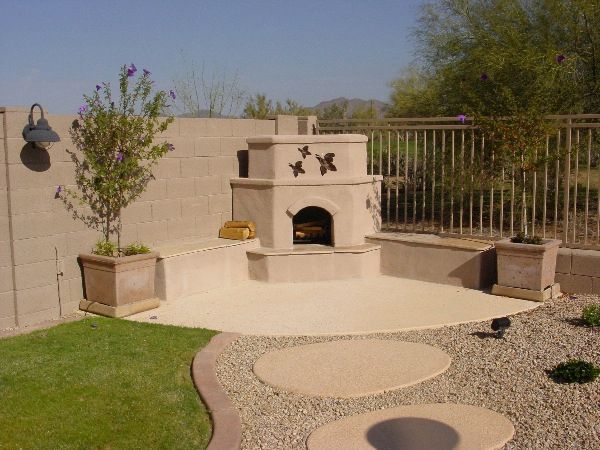 A patio with a fireplace and a fence in the background