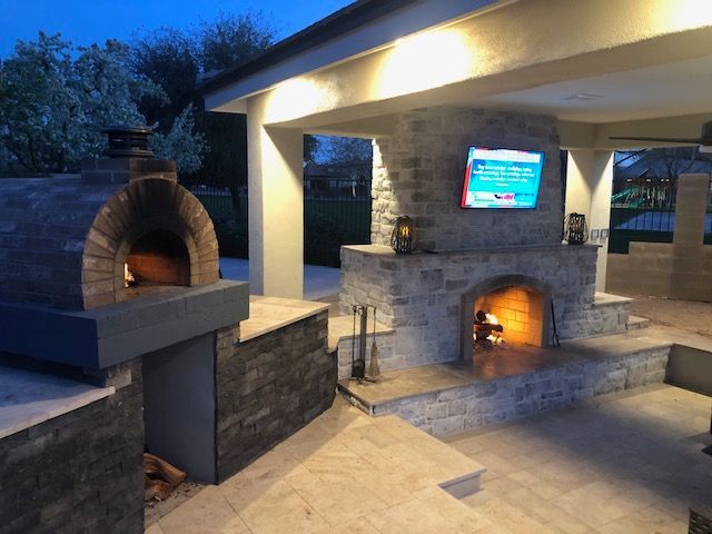 A brick oven is sitting next to a fireplace and a television.