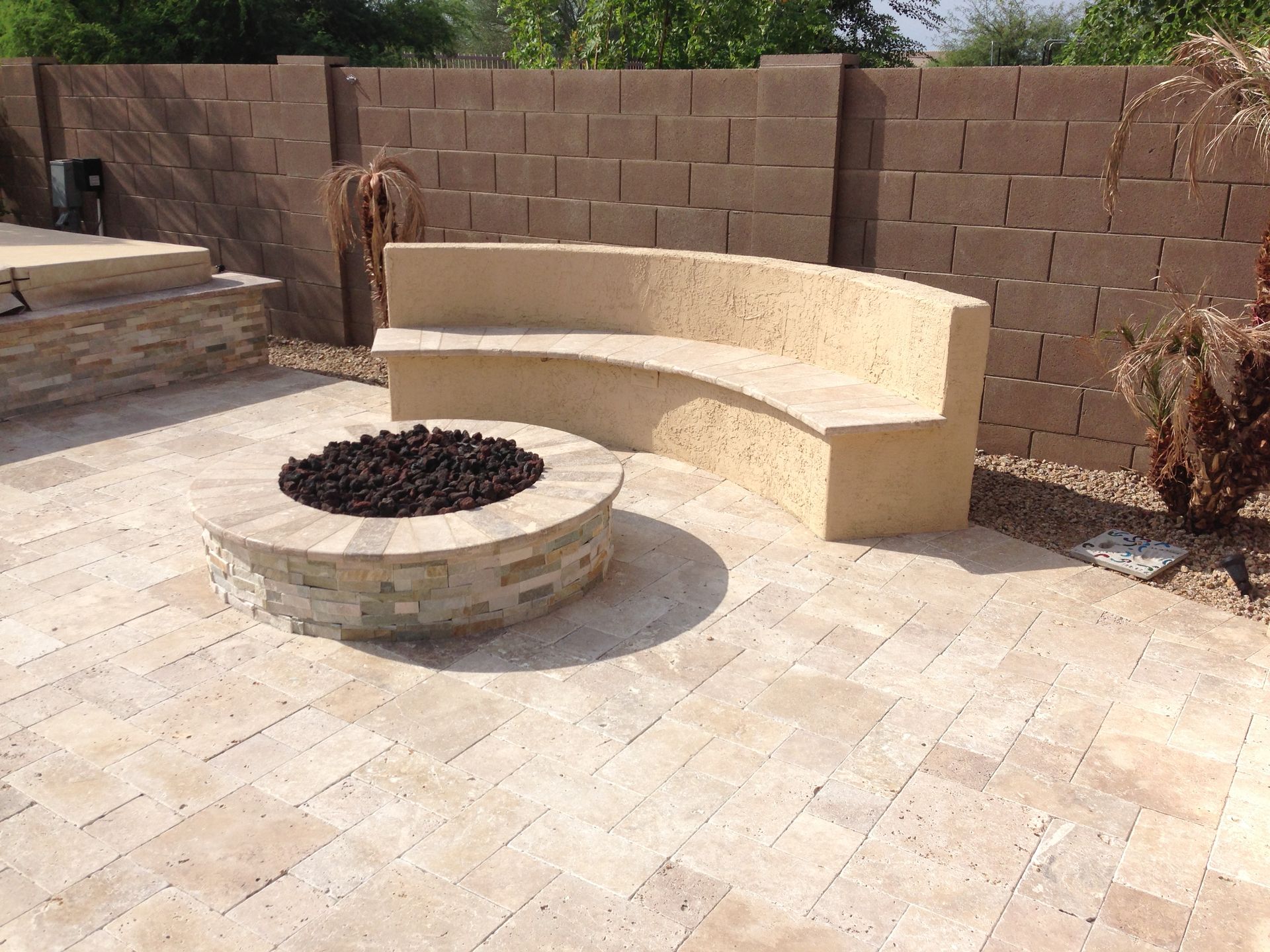 A patio with a fire pit and a curved bench