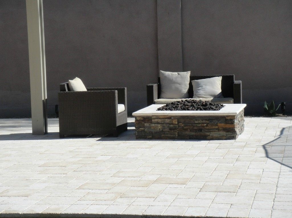 A patio with a fire pit and a couch and chairs