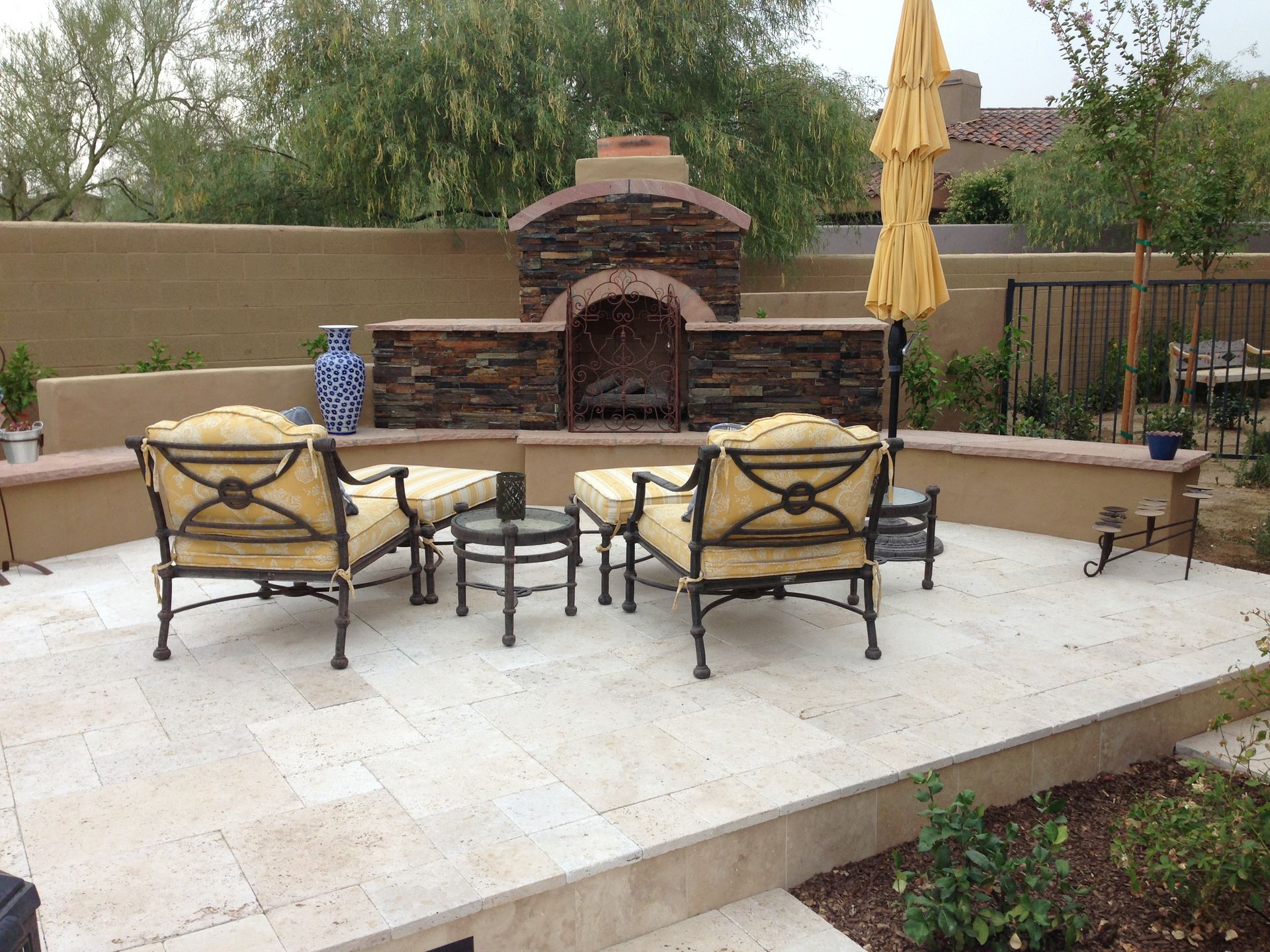 A patio with a fireplace and chairs and umbrellas