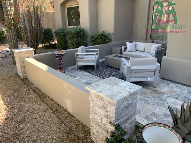 A patio with a couch , chairs , and a table in front of a house.