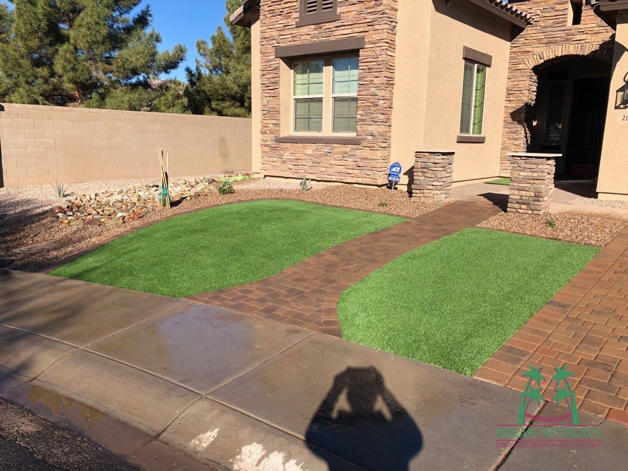 A person is taking a picture of a lawn in front of a house.